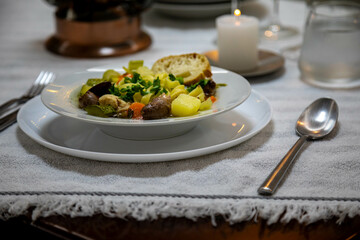 Luxurious table setting with white plates, crystal glasses and fine cutlery. Soup