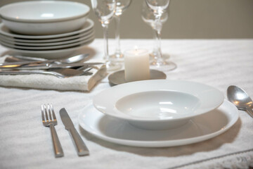 Luxurious table setting with white plates, crystal glasses and fine cutlery
