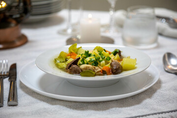 Luxurious table setting with white plates, crystal glasses and fine cutlery. Soup