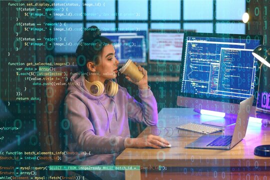 Young female programmer drinking coffee while working in office