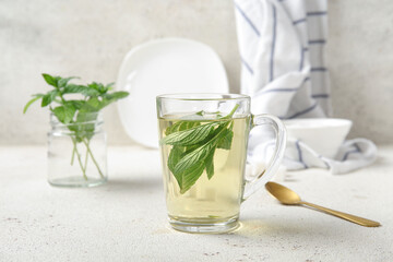 Cup of fresh mint tea with spoon on grunge light table