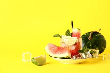 Glass of fresh watermelon lemonade with lime and mint on yellow background