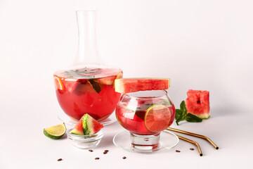 Glass and bottle of fresh watermelon lemonade with lime on white background