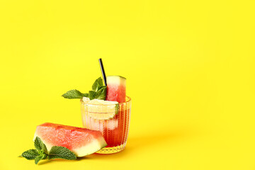 Glass of fresh watermelon lemonade with lime and mint on yellow background