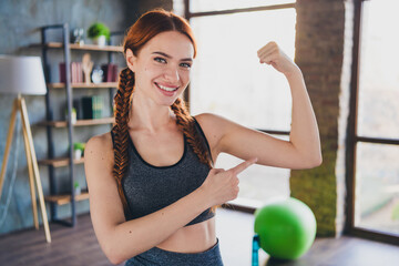 Fototapeta premium Portrait of beautiful young nice sportswoman point finger biceps training activity flat indoors