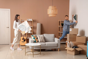 Happy young couple with paintings in room on moving day