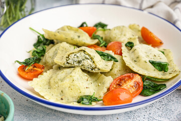 Bowl of tasty ravioli with vegetables on grey background