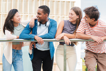 Diverse group of teenage students talking on a university campus railing after classes. Multiracial...