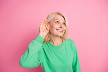 Photo portrait of nice pensioner woman look empty space listen news wear trendy green outfit isolated on pink color background