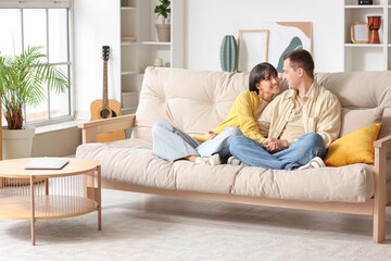 Young couple in love hugging on sofa at home