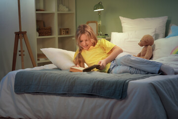 Adorable girl reading fairy tale before sleep in bed