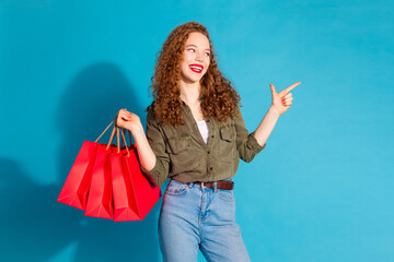 Portrait of pretty young woman indicate finger empty space wear khaki shirt isolated on turquoise...