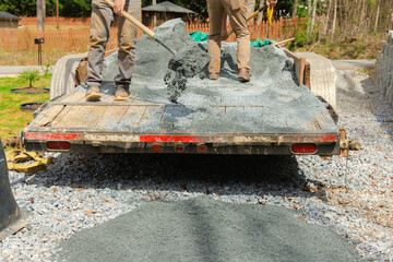 When leveling driveway, workers filling parking lot near house with small stone