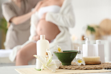 Bottles of cosmetic products with flowers on table in spa salon, closeup