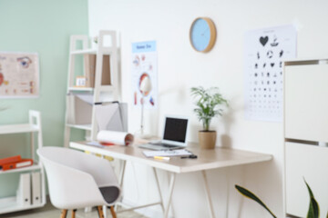 Blurred view of ophthalmologist's office with workplace and eye test chart