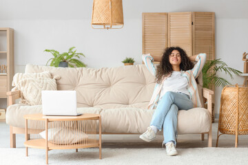 Young African-American woman resting on couch at home