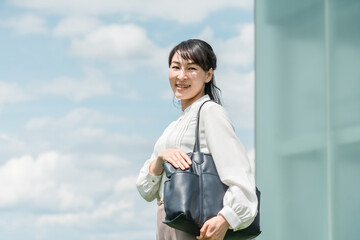 青空の屋上にいるビジネスウーマン（ワーキングマザー・通勤・転職）
