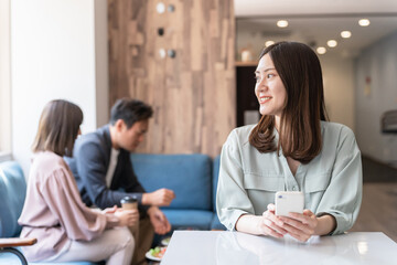カフェでスマホを使う若いアジア人女性・ビジネスウーマン・大学生
