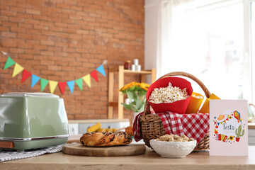 Wicket basket with popcorn, peanuts and greeting card on table in kitchen. Festa Junina celebration