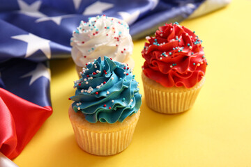 Tasty patriotic cupcakes with USA flag on yellow background. American Independence Day