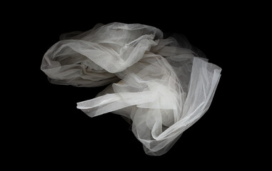 Fototapeta premium White organza lace fabric flying in curve shape, Piece of textile White organza lace fabric throw fall in air. Black background isolated, dark shading environment