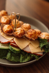 Sandwich bubble waffle with meat, cheese and herbs in a plate on a wooden table.