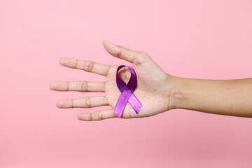 Hand Holding Purple Ribbon On Palm Over Pink Background. World Epilepsy Day. Alzheimer's Disease, Pancreatic Cancer.