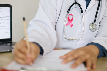 Doctor With White Coat Writting On Medical Document Wearing Pink Ribbon And Stethoscope