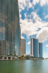 Obraz premium Highrise towers on the Miami River. Florida USA 2024. Long exposure with motion blur in water and clouds