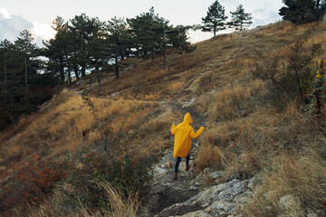 A person wearing a yellow raincoat walking up a steep hill with an umbrella in hand on a rainy day