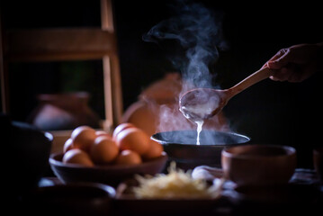 A porridge shop at night on the side of the road as the cook uses a wooden ladle to scoop porridge into a wooden bowl in a retro style. There were eggs and sliced ​​ginger placed on the table.