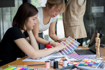Fototapeta premium Young team asian designer women working at studio. Dressmaker makes clothes job