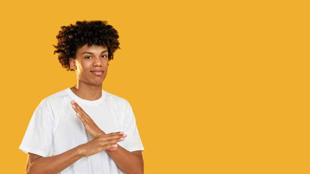 Refusal gesture. Stop enough. Displeased skeptic disappointed guy rejecting with x crossed arms no signal isolated on yellow empty space background.