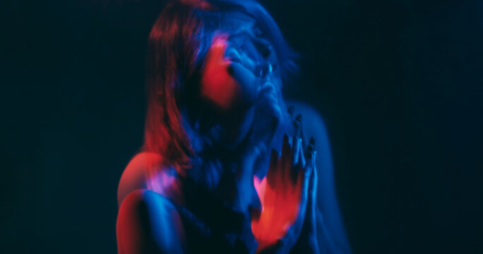 Split mind. Blur woman. Worried pleading silhouette folding hands hoping help neon red blue color dark double exposure out of focus copy space.