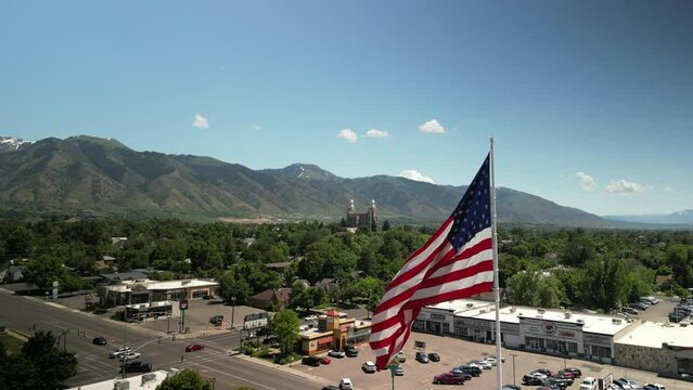 Aerial around American Flag in Logan Utah on sunny spring day