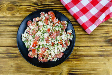 Salad with tomatoes, cottage cheese, dill and olive oil on a wooden table. Top view