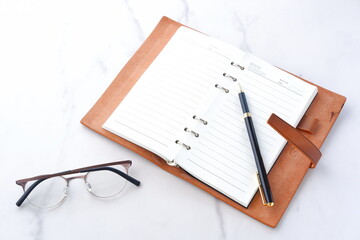 リング式のシステム手帳を開いてデスクワークをしているイメージ
