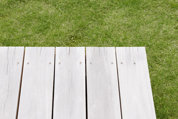 芝生背景にヴィンテージな木目のテーブル。キャンプやアウトドアイメージのディスプレイ