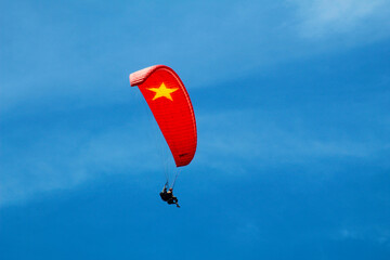 Photograph of a paraglider soaring against a clear blue sky. Captures the thrill and freedom of...