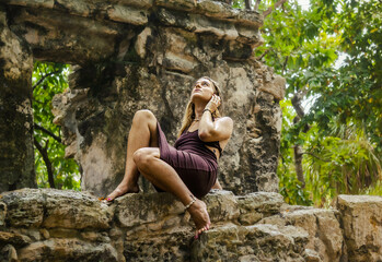 Girl on a dress posing on a Mayan Archeological site in the Jungle of Yucatan