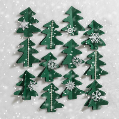 Minimal pattern from Green Christmas trees cut of paper on white fur, winter holiday card, falling snow. Handmade green tree firs decorated snowflakes, pearls. Aesthetic top view, xmas holiday