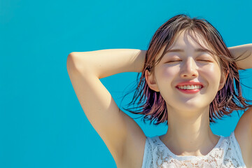 Fototapeta premium Beautiful young Asian woman relaxing against a blue background with a serene expression on her face. 
