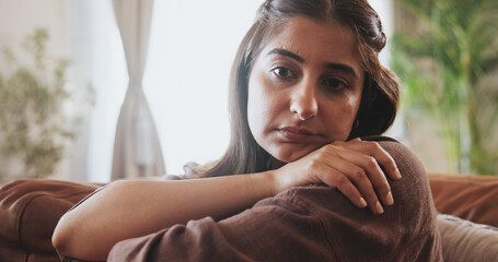 Fototapeta premium Sad, woman and thinking on sofa house with mistake anxiety, depression and for conflict of memory reflection. Pensive, female person and doubt of mental health, trauma and perspective of solution