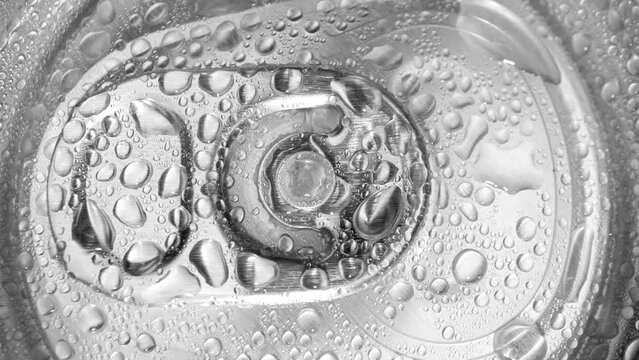 Glistening with droplets, the aluminum lid of the can offers a tantalizing glimpse of refreshment. The pull tab invites exploration, promising a burst of coolness within. Can background.
