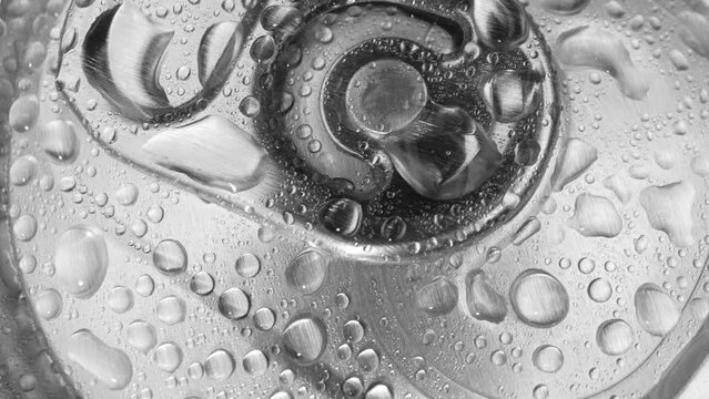 A glistening landscape of tiny water droplets adorning the aluminum can's surface. The pull-tab gleams, inviting a refreshing sip. Metallic elegance in miniature. Beverage background.
