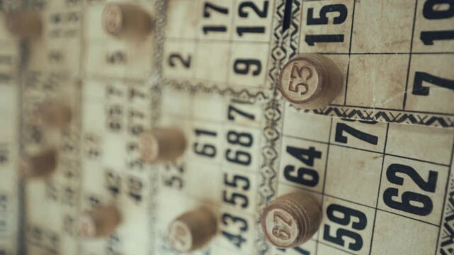 Macro video of a Bingo board, studio lights, 120 fps, slow motion, wooden chip digits, Raw footage, lottery desk game, card numbers, crane pull back dreamy rotating movement