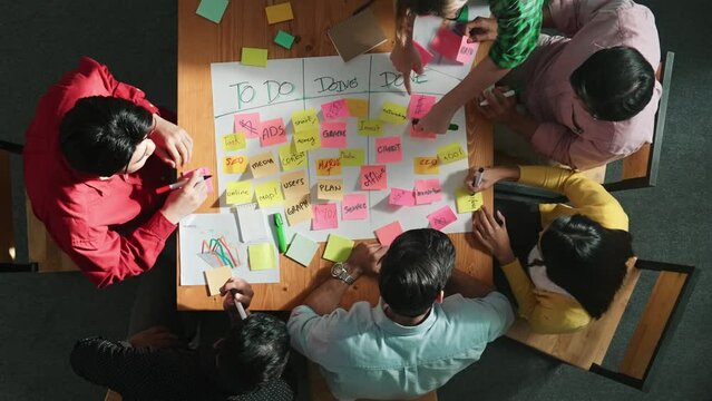 Top view of people writing and making scrum task board while writing marketing and planning strategy at colorful sticky notes. Smart team manage work performance by using kanaban board. Convocation.