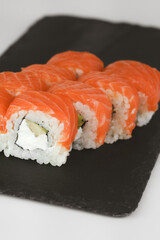 Closeup of fresh salmon sushi rolls served on a black slate plate