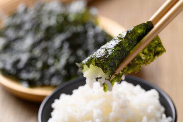 Dried seaweed sheet eating with rice by chopsticks, Asian food © nungning20