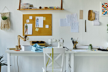 A clean and well-organized workspace of a DIY clothing restoration atelier, featuring a sewing machine, fabrics, design sketches